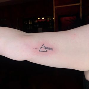 Fine line and ignorant style tattoo featuring the iconic triangle from Pink Floyd's Dark Side of the Moon album. By artist Liam Collins.