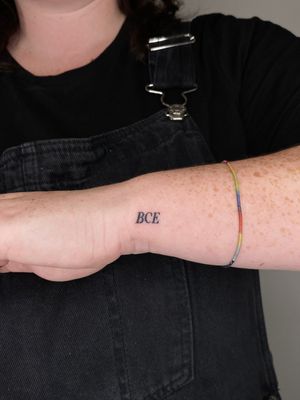Get a chic and understated small lettering tattoo on your wrist by talented artist Liam Collins. Perfect for a subtle but stylish look.