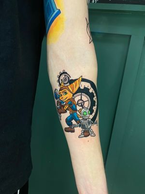 Get a playful and colorful anime-themed tattoo inspired by the beloved Playstation game Ratchet & Clank, created by talented artist Liam Collins.