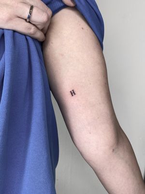 Get a small letter 'h' tattoo on your arm by talented artist Liam Collins. Simple yet meaningful design.