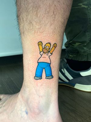 Get a bold and colorful rendition of everyone's favorite cartoon dad, Homer Simpson, by tattoo artist Liam Collins. Perfect for fans of The Simpsons and comic art!