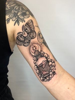 Experience the mystical allure of dotwork and neo-traditional style with this stunning tattoo featuring a moon, star, moth, teeth, and bottle. By tattoo artist Liam Collins.