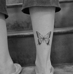 A black and gray butterfly tattoo on the lower leg, expressing Monike's unique style.