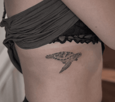 Black and gray micro realism tattoo of a sea turtle, beautifully done by Monike on the ribs.