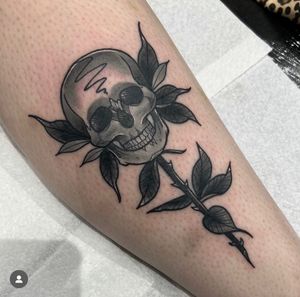 Unique traditional design by Katy Sarsfield, combining a vibrant rose with a haunting skull on the shin area.