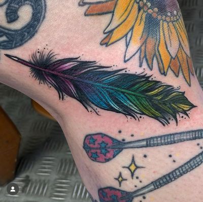 Elegant neo-traditional feather design by tattoo artist Katy Sarsfield, beautifully placed on the knee for a unique and striking look.