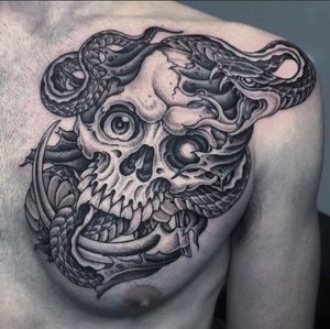 A striking black and gray illustrative tattoo featuring a snake and skull, expertly done by tattoo artist Gianluca Fusco.