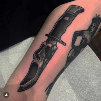 Dazzle with this neo-traditional, illustrative tattoo masterpiece by Katy Sarsfield featuring a spooky ghost face with a knife inspired by iconic horror movies like Scream.