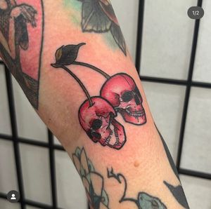 Vibrant neo-traditional illustrative tattoo by Katy Sarsfield featuring a skull and cherry bunch motif. Bold colors and intricate details.