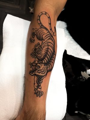 Experience the fierce beauty of a traditional Japanese tiger tattoo on your lower arm by the talented artist Barney Coles.