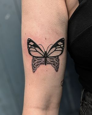 Unique blackwork dotwork hand_poke tattoo of a butterfly on ribcage by Alien Ink, combining illustrative elements.