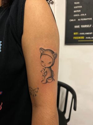 Get a whimsical anime tattoo by Jack Howard featuring a harmless kitty, in the style of Yoshitomo Nara, on your arm.