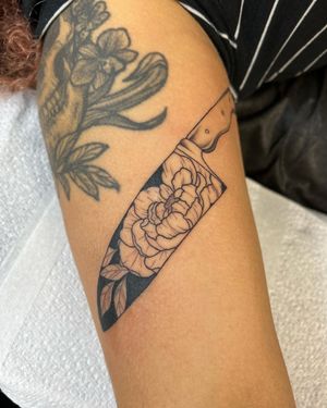 A beautiful illustrative tattoo featuring a flower and knife, skillfully designed by Jack Howard.