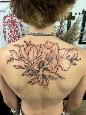 Adorn your upper back with a beautiful floral design featuring flowers and leaves, expertly crafted by tattoo artist Jack Howard.