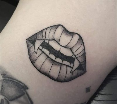 Traditional tattoo of vampire teeth sinking into lips, by Elisa Thirteen.