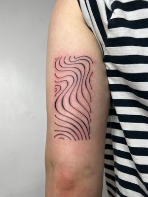 Elegant and minimalistic tattoo by Dan Bramfitt, featuring wavy lines that create a sense of movement and grace.