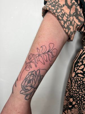 Illustrative tattoo of a delicate plant branch with leaf, by artist Danyul.