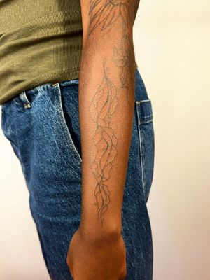Discover the beauty of dark skin in this illustrative tattoo by Dan Bramfitt. Flowy, wavy lines create a unique and captivating design.