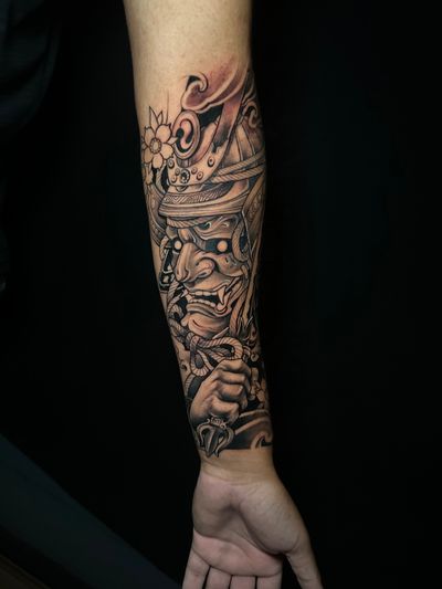 Experience the strength and honor of the samurai with this powerful black and gray Japanese illustrative tattoo by Avi.