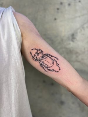 Get a sleek and stylish fine line tattoo of a single line beetle by Well Good Mate for a modern and unique look.
