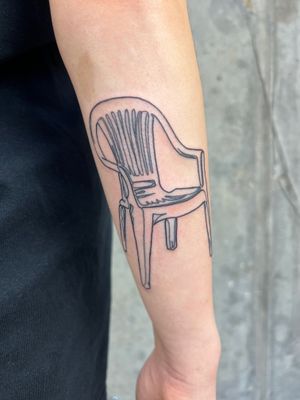 Get a unique and bold tattoo of a chair on your lower arm, done by the talented artist Well Good Mate. Stand out from the crowd with this edgy design!