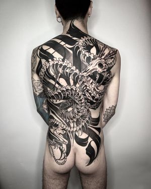 Embrace the dark side with this striking blackwork illustration of a dragon intertwined with a skeleton, expertly crafted by tattoo artist Helena Velazquez.