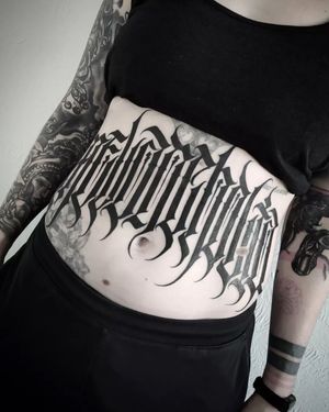 Express yourself with a unique lettering tattoo on your stomach, expertly done by Helena Velazquez.