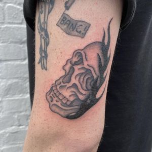 Embrace the classic style with this bold traditional skull tattoo done by the talented artist Charlie Macarthur.