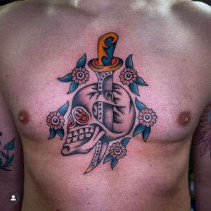 Intricately inked by tattoo artist Sam Young, this traditional chest tattoo features a menacing skull and sharp dagger motif.