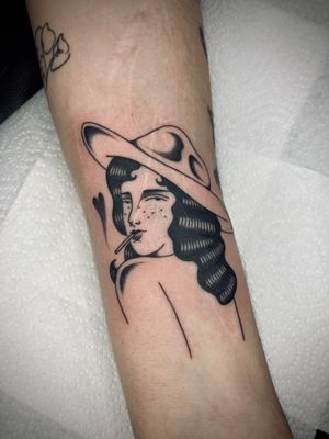 Get inked with a striking traditional tattoo of a woman wearing a hat, designed by the talented artist Rachel Arfin.