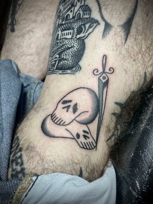 Get a bold and vibrant traditional tattoo featuring a skull and sword design done by the talented artist Rachel Arfin.