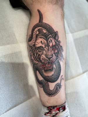 Get a striking neo traditional tattoo featuring a snake and tiger by artist Joni Smith. Perfect blend of nature and strength.