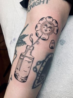 Get inked with a unique dotwork and traditional style tattoo featuring a daisy flower, bottle, and face by the talented artist, Rachel Arfin.