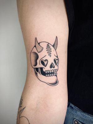 Get inked with a fierce traditional tattoo by Rachel Arfin featuring a skull and devil motif, showcasing bold lines and vibrant colors.