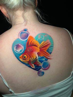 Dive into a sea of colors with this stunning upper back tattoo of a fish, beautifully done by Cloto.tattoos.