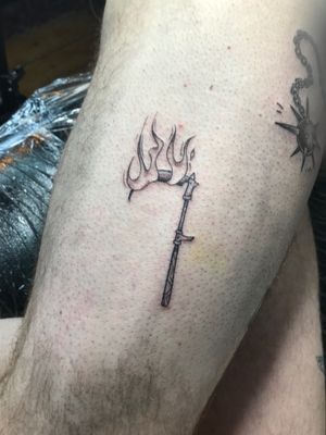 Unique and bold tattoo design featuring a scythe engulfed in flames, created by the talented artist Jonathan Glick.