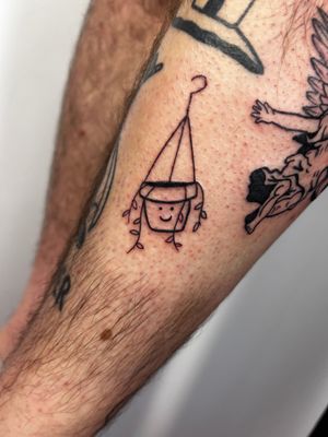 Ignorant style tattoo featuring a hanging plant and smiley motif on lower leg by Jonathan Glick.