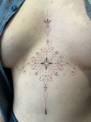 Elegant ornamental design on the sternum by Indigo Forever Tattoos. Make a bold statement with this intricate motif.