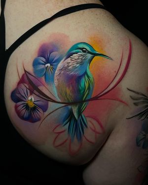 Stunning watercolor tattoo of a bird by Cloto.tattoos, beautifully placed on the hip. Expertly blending colors for a unique and artistic design.