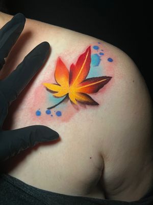 Vibrant watercolor tattoo featuring a leaf and amber tree, beautifully crafted by Cloto.tattoos on the shoulder.