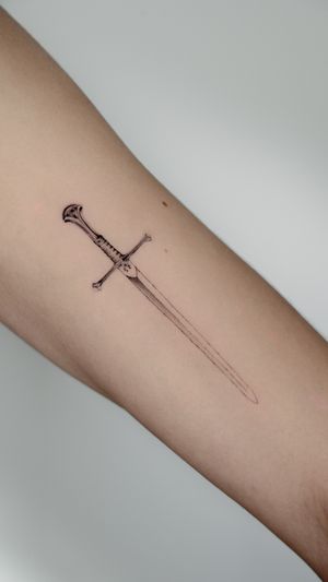 Elegant fine line sword tattoo on upper arm, expertly done by tattoo artist Jacky Yang. Embrace your inner warrior with this stylish design.