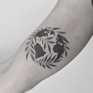 Illustrative tattoo by Oliver Whiting featuring intricate dotwork design of map and globe with delicate leaves.