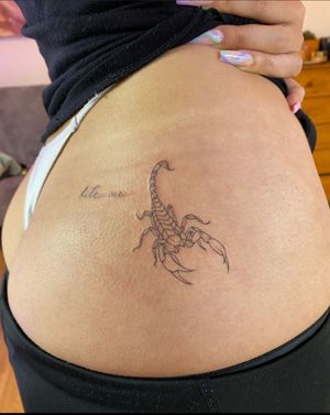 A small, illustrative scorpion tattoo with the words 'Bite Me' in small lettering. Created by artist Ion Caraman.