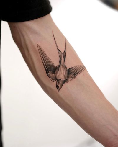 Capture the beauty of nature with this stunning black and gray swallow tattoo by Ion Caraman. Perfect for a bold statement on your forearm.