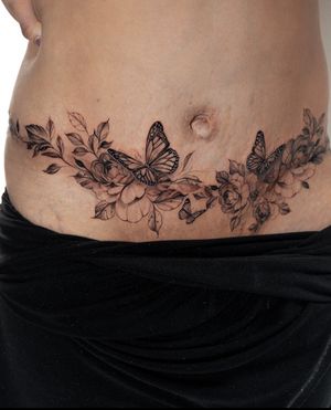 Get mesmerized by Ion Caraman's stunning black and gray floral tattoo featuring a delicate butter motif on your stomach.