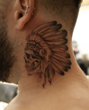Detailed black and gray tattoo featuring a skull wearing a war bonnet, expertly done by Ion Caraman.