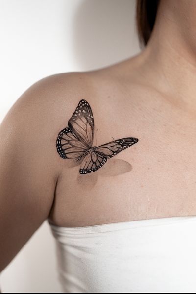Stunning shoulder tattoo of a lifelike butterfly in black and gray, expertly done by artist Ion Caraman.