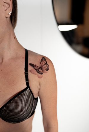 Elegant black and gray butterfly tattoo on the shoulder by Ion Caraman, showcasing intricate details and lifelike design.