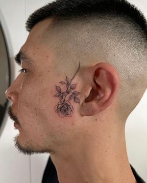 Capture the timeless beauty of a rose with this striking traditional style side face tattoo by Ion Caraman.