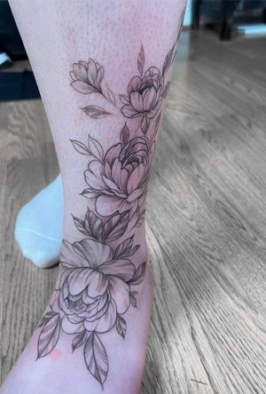 Adorn your ankle with a beautiful flower motif tattoo by Ion Caraman, showcasing intricate floral details.